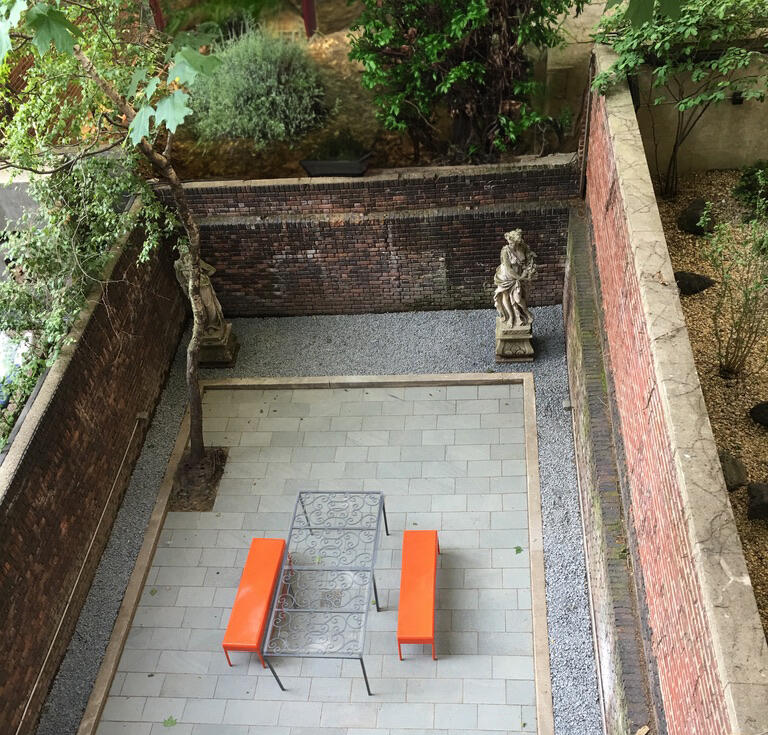 Bespoke glass topped table in urban garden made from wrought iron gates formerly on the windows of the townhouse.